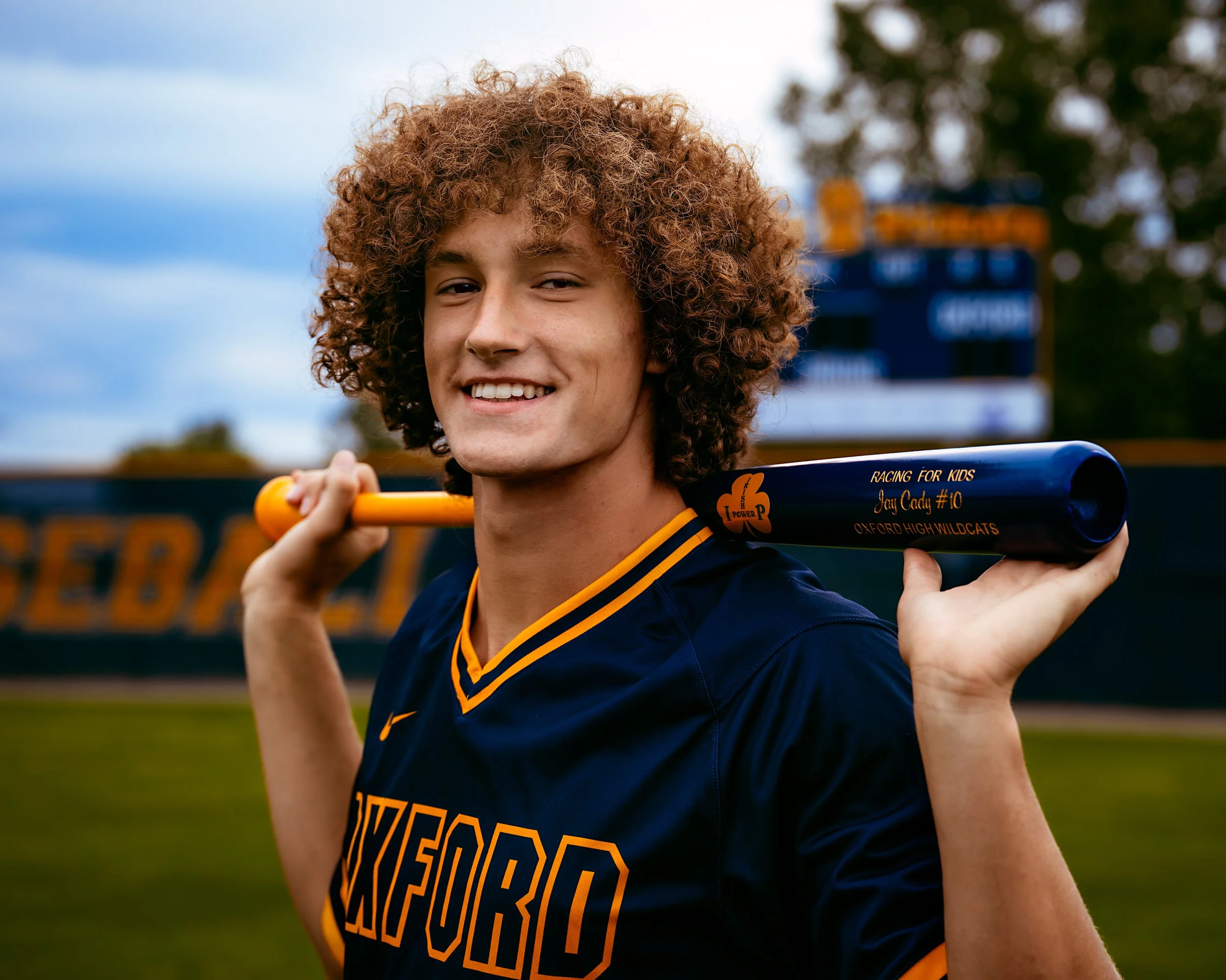 Man looking into camera while holding a baseball bat at High School Senior Photography Session with Two Wild Souls Photography