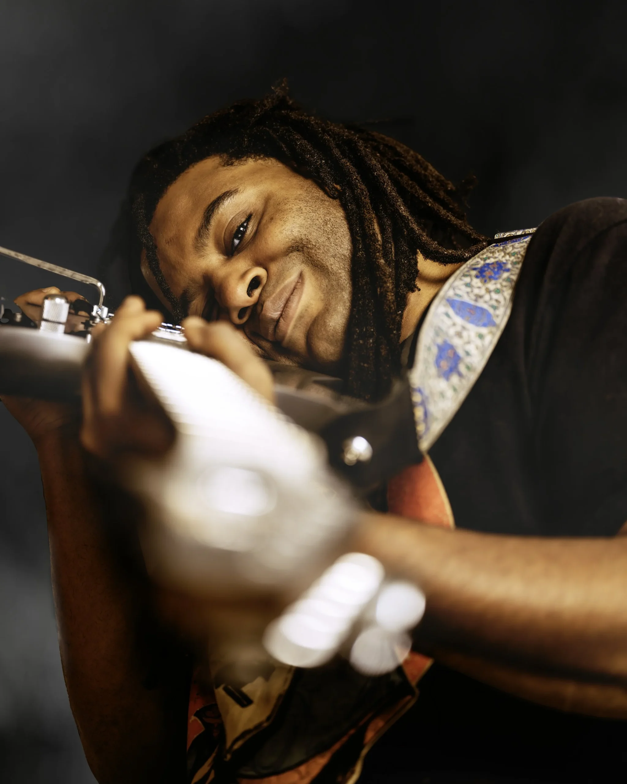 Person playing electric guitar with close-up view and detailed strap design.
